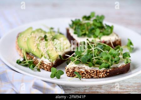 Roggenbrot mit Cerealien, Frischkäse, Avocado und Sprossen aus Rettich (mikrogrün) Stockfoto