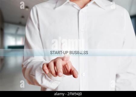 Geschäftsmann drückt Start-up-Business-Taste auf einem virtuellen Bildschirm. Unternehmensneustart oder Investition in ein neues Geschäftskonzept Stockfoto