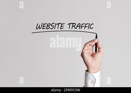 Geschäftsmann Hand mit Stift unterstreicht die Worte Website-Verkehr auf einem grauen Hintergrund virtuellen Bildschirm. Stockfoto