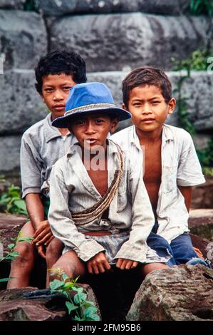 Drei Jungen sitzen auf den Steinen am Tempelberg Ta Keo, auch Prasat Keo genannt, und blicken neugierig in die Kamera. 30.06.1991 - Christoph Keller Stockfoto