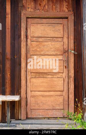 Alte russische Tür mit abblätternder Farbe in der Holzwand des Hauses. Vertikales Bild. Stockfoto