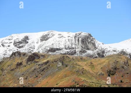 Dove Crag bedeckt mit Frühlingsschnee mit dem Priest Hole Just Visible, Dovedale, Eastern Lake District, Cumbria, Großbritannien Stockfoto