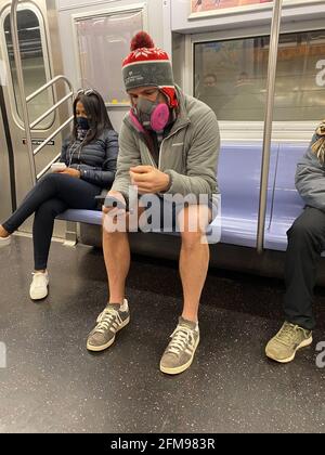 Während der Pandemie von Covid-19 in New York City trägt der Mann eine sehr ernst aussehende Gesichtsmaske in einem U-Bahn-Zug. Stockfoto