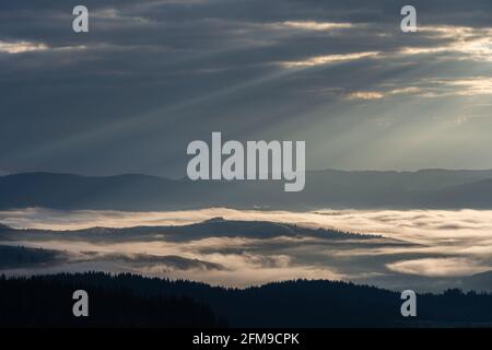 Schöner Sonnenaufgang über Hügeln und Landschaft. Neblige Morgenlandschaft mit dramatischem Himmel Stockfoto