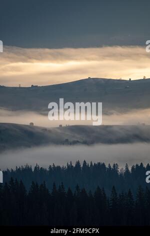 Schöner Sonnenaufgang über Hügeln und Landschaft in den Karpaten. Neblige Morgenlandschaft mit dramatischem Himmel Stockfoto