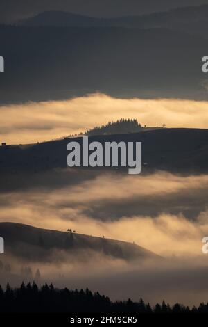 Schöner Sonnenaufgang über Hügeln und Landschaft. Neblige Morgenlandschaft mit dramatischem Himmel Stockfoto