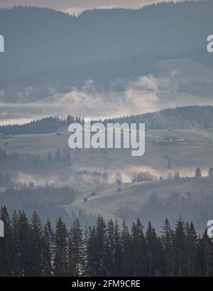 Schöner Sonnenaufgang über Hügeln und Landschaft. Neblige Morgenlandschaft mit dramatischem Himmel Stockfoto