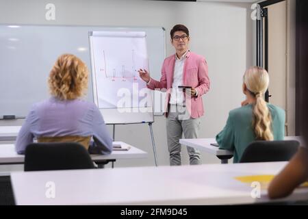 Asiatischer Mann, der seinen Bürokollegen in eine Präsentation gibt Tagungsraum im Büro Stockfoto