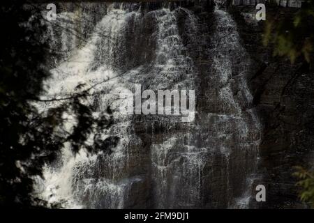 Graustufenaufnahme eines Wasserfalls über Klippen - perfekt Für den Hintergrund Stockfoto