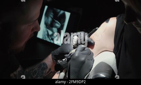 Mann macht schwarze Tätowierung von Schlange im Studio Stockfoto