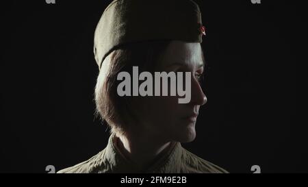 Foto einer Frau, die im Schatten eine sowjetische rote Armeeuniform trägt Stockfoto