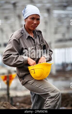 Eine Bauarbeiterin passt ihren Helm auf einer großen Baustelle für eine Industriesiedlung am Stadtrand von Hanoi an. 04/1994 - Christoph Kel Stockfoto