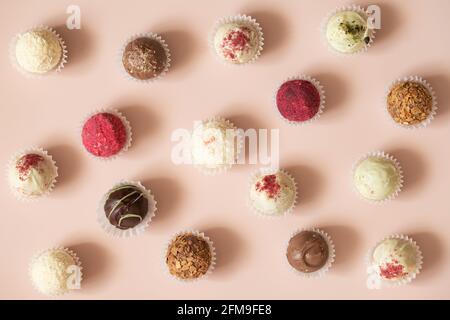 Candy-Hintergrund. Verschiedene Trüffel oder Energiekugeln auf einem rosa Hintergrund. Süßigkeitenmuster. Draufsicht, flach liegend. Stockfoto