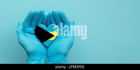 Ärzte Hände tragen chirurgische Handschuhe halten Bahamas Flagge Herz Stockfoto