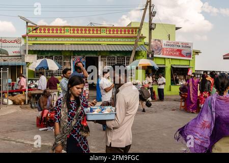 Mysuru, Karnataka, Indien - 2019. Januar: Ein indischer Straßenhändler, der vor dem alten Chamundeshwari-Tempel in Chamu religiöse Gegenstände an eine Frau verkauft Stockfoto