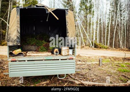 Ein Raupentraktor fährt durch eine Waldlichtung. Ein industrieller Bulldozer steckt im Schlamm fest. Lastwagen laufen im Boden Stockfoto