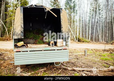 Ein Raupentraktor fährt durch eine Waldlichtung. Ein industrieller Bulldozer steckt im Schlamm fest. Lastwagen laufen im Boden Stockfoto