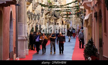 Italien, Sizilien, Taormina, Stadtzentrum, Fußgängerzone, Weihnachtsschmuck, Passanten, lachsfarbene historische Gebäude links und rechts Stockfoto