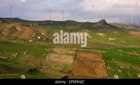 Italien, Sizilien, Catania, Raddusa, SP114, Strada Provinciale 114, hügelige Landschaft, Felder, grüne Wiesen, Felsbrocken, Windgeneratoren auf Bergrücken, isolierter Gehöft Stockfoto