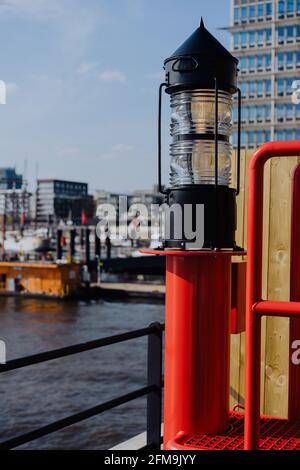 Rotlichtlaterne in der HafenCity, Hafenpiers mit Schiffen und Jacht vor Anker im Hintergrund. Hamburg, Deutschland. Vertikale Aufnahme Stockfoto