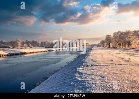 Sonnenaufgang in Wiesmoor, Eastfrisa an einem kalten Wintermorgen mit Schnee und einem bunten Sonnenaufgang. Stockfoto