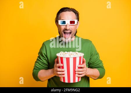 Foto von verrückten Borsten Kerl halten Papierbox Popcorn tragen 3d-Brille grünen Pullover isoliert gelben Hintergrund Stockfoto