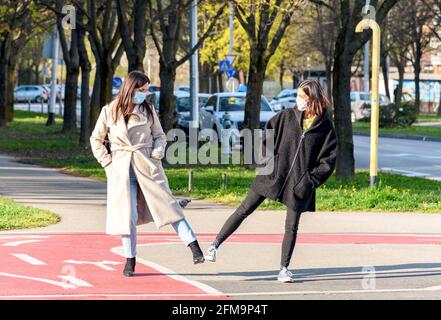 Zwei Frauen mit Gesichtsmasken stehen auf dem Bürgersteig in der Stadt. Stockfoto