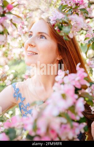 Nahaufnahme eines rothaarigen Mädchens in einer rosa Magnolie. Stockfoto