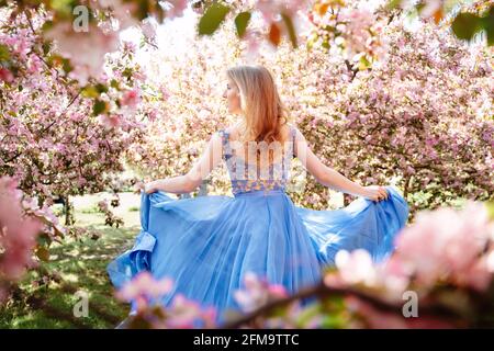 Eine Frau rennt im Frühling in einem blühenden Apfelgarten. Stockfoto