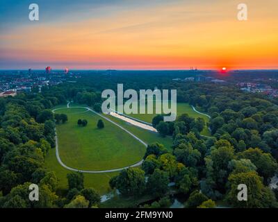 Wunderbarer Gesamtblick über den Englischen Garten von München bei einem sommerlichen Sonnenaufgang. Der grüne öffentliche Sightseeing-Hotspot wurde von oben gefilmt Stockfoto