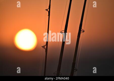 Sonnenuntergangs-Landschaft mit Angelruten Silhouetten in Huntington Beach, Orange County California, USA. Stockfoto