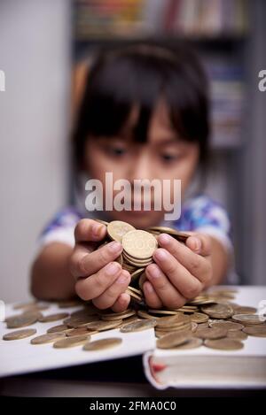 Kleines nettes Mädchen zählt Haufen Münzen Stockfoto
