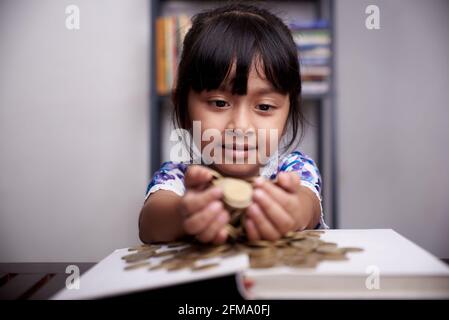 Kleines nettes Mädchen zählt Haufen Münzen Stockfoto