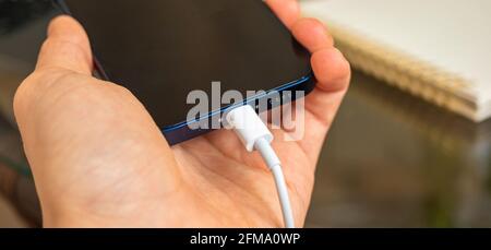 Kharkov, Ukraine - 27. April 2021: Mann verwenden Lightning-Anschluss zum Aufladen des Apple iPhone 12 Stockfoto