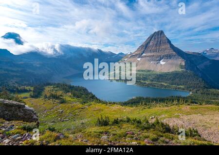 Hidden Lake und der pyramidenförmige Bearhat Mountain im Glacier National Park, Montana, USA. Am frühen Morgen Licht und verstreute Wolken über Alpental i Stockfoto