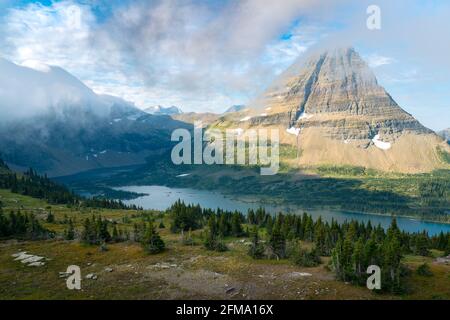 Hidden Lake und der pyramidenförmige Bearhat Mountain im Glacier National Park, Montana, USA. Am frühen Morgen Licht und verstreute Wolken über Alpental i Stockfoto