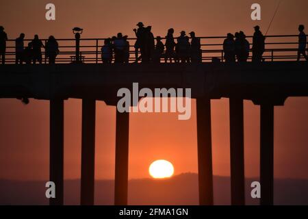 Sonnenuntergangslandschaft mit Silhouetten von Menschen am Huntington Beach Pier in Orange County, Kalifornien, USA. Stockfoto