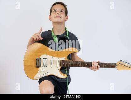 Ein kleiner Junge singt und spielt auf der E-Gitarre mit Index-up, isoliert auf weißem Hintergrund Stockfoto