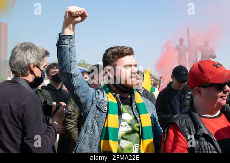 Protest gegen Glazer auf dem Old Trafford Fußballplatz. Supporter hält die Faust hoch und trägt einen grünen und goldenen Schal Stockfoto