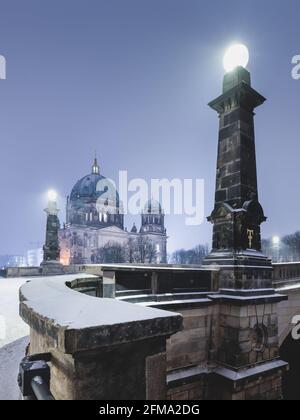 Verschneite Nacht im Winter auf der beleuchteten Friedrichbrücke am Berliner Dom auf der Museumsinsel. Stockfoto