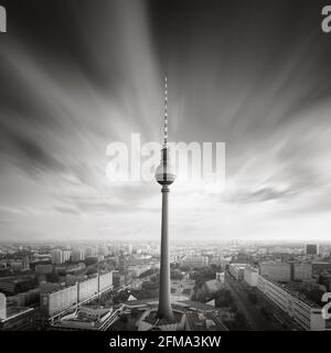 Lange Exposition von vorbeiziehenden Wolken über dem Berliner Fernsehturm mit Blick auf die Hauptstadt in Schwarz-Weiß. Stockfoto