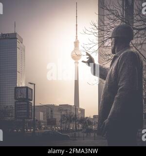 Sonnenuntergang hinter dem Fernsehturm auf dem Berliner Alexanderplatz mit einer historischen Statue im Vordergrund. Stockfoto