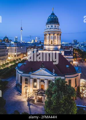 Abenddämmerung auf dem beleuchteten Berliner Gendarmenmarkt mit dem Französischen Dom und dem Deutschen Dom sowie dem Berliner Fernsehturm im Hintergrund. Stockfoto