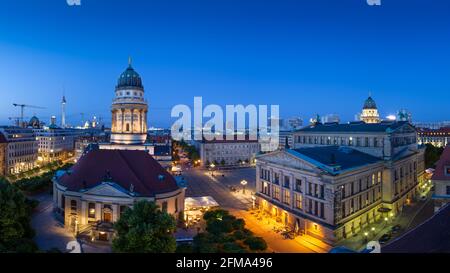 Abenddämmerung auf dem beleuchteten Berliner Gendarmenmarkt mit dem Französischen Dom und dem Deutschen Dom sowie dem Berliner Fernsehturm im Hintergrund. Stockfoto