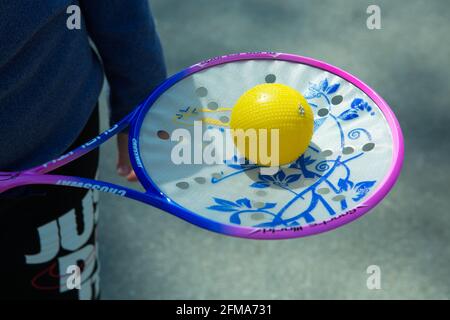 Dnepropetrovsk, Ukraine - 04.22.2021: Ein Mann hält einen Tennisschläger mit einem Ball in der Hand. Stockfoto