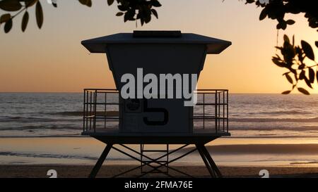 Rettungsschwimmer-Wachturm, sonniger Strand bei Sonnenuntergang, Oceanside USA. Rettungsstation, Watchtowerhütte am Wasser und Baumblätter, Atmosphäre an der pazifikküste. Kalifornische Sommerästhetik, Los Angeles vibes. Stockfoto