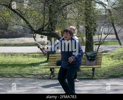 Dnepropetrovsk, Ukraine - 04.22.2021: Eine Gruppe von Senioren tun Gesundheit und Fitness-Gymnastik im Park. Alte Männer machen Tennisball und Schlägerübungen. Stockfoto