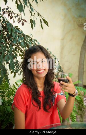 Porträt einer lächelnden jungen hispanischen Frau mit einem Glas Rotwein - Casa Amorita B&B, Puerto Vallarta, Jalisco, Mexiko. #613 PV Stockfoto