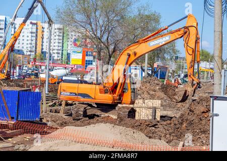 Samara, Russland - 06. Mai 2021: Orangefarbener Bau-Einkübel-Raupenbagger im Sommer Stockfoto