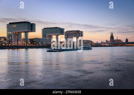 Kranhäuser am Rheinufer in der Abenddämmerung, mit dem Kölner Dom im Hintergrund Stockfoto